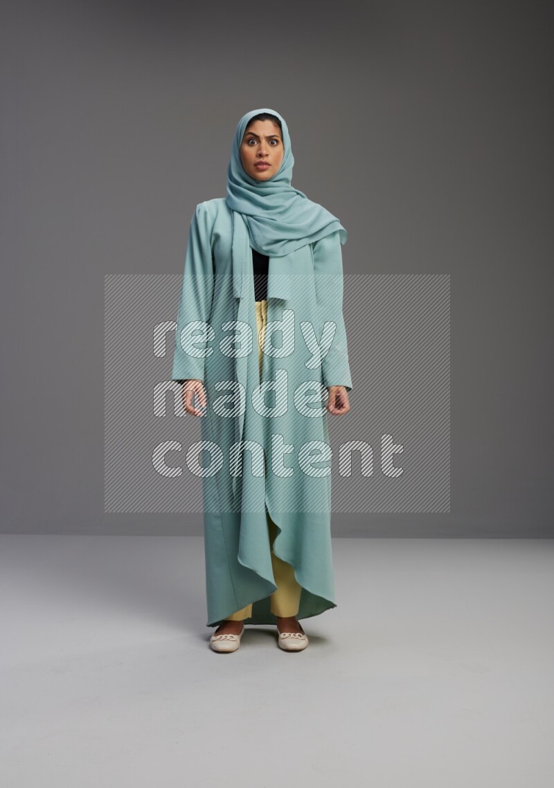 Saudi Woman wearing Abaya standing interacting with the camera on Gray background