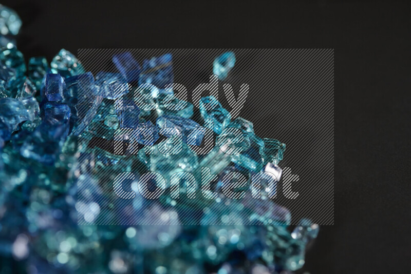 Transparent blue fragments of glass scattered on a black background
