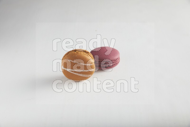 45º Shot of of two assorted Brown Irish Cream, and Red Cherry macarons on white background