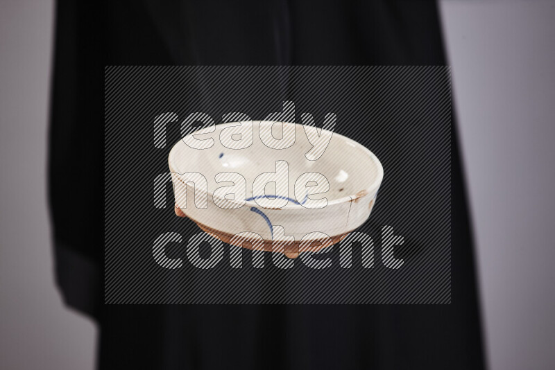 A woman in black abaya holding different pottery essentials in different positions