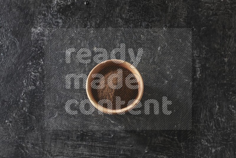 وعاء خشبي ممتلئ ببودرة القرنفل علي خلفية سوداء