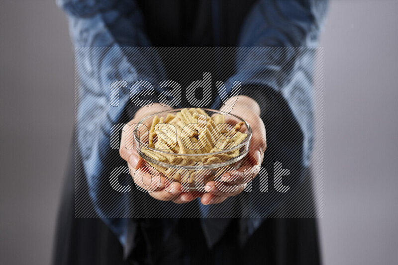Woman in abaya holding different kinds of snacks in different positions
