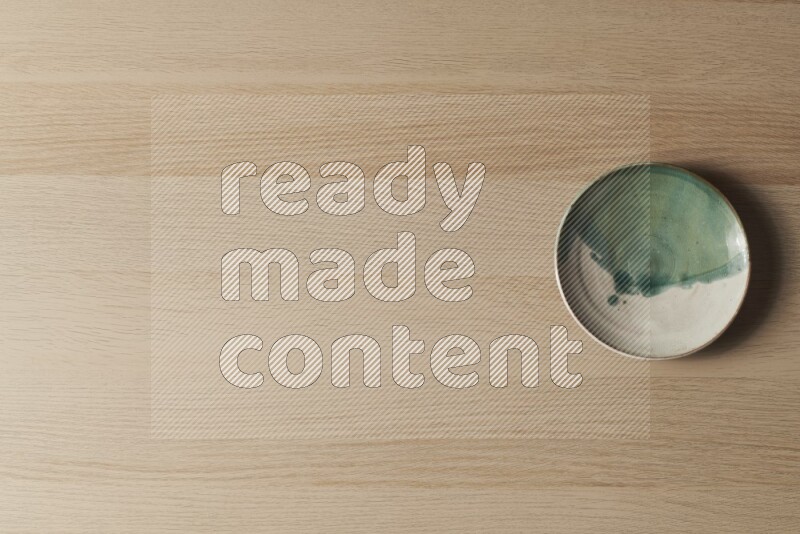 A multicolored pottery plate on light wooden background