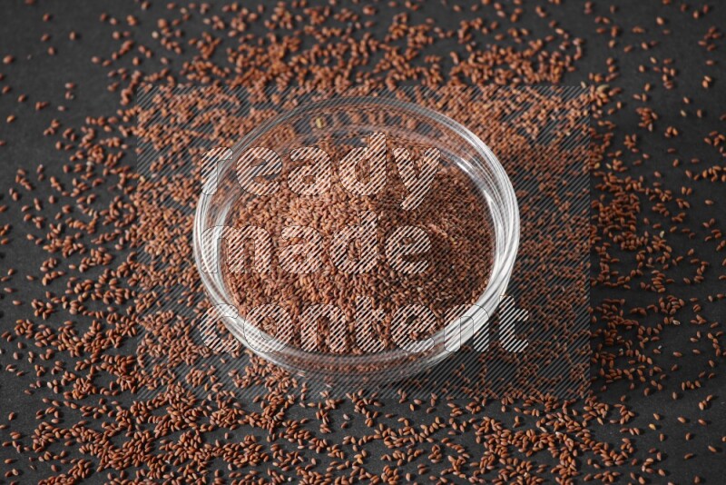 وعاء زجاجي ممتلئ ببذور حب الرشاد محاط بالبذور على أرضية سوداء