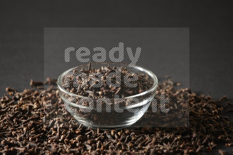 A glass bowl full of cloves on a black flooring