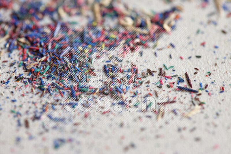 This image showcases a vibrant multicolored pencil shavings scattered on grey background