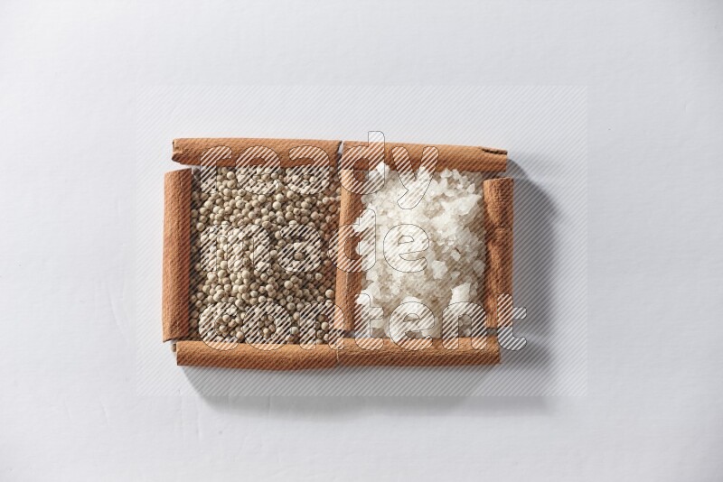 2 squares of cinnamon sticks full of white pepper and white salt on white flooring