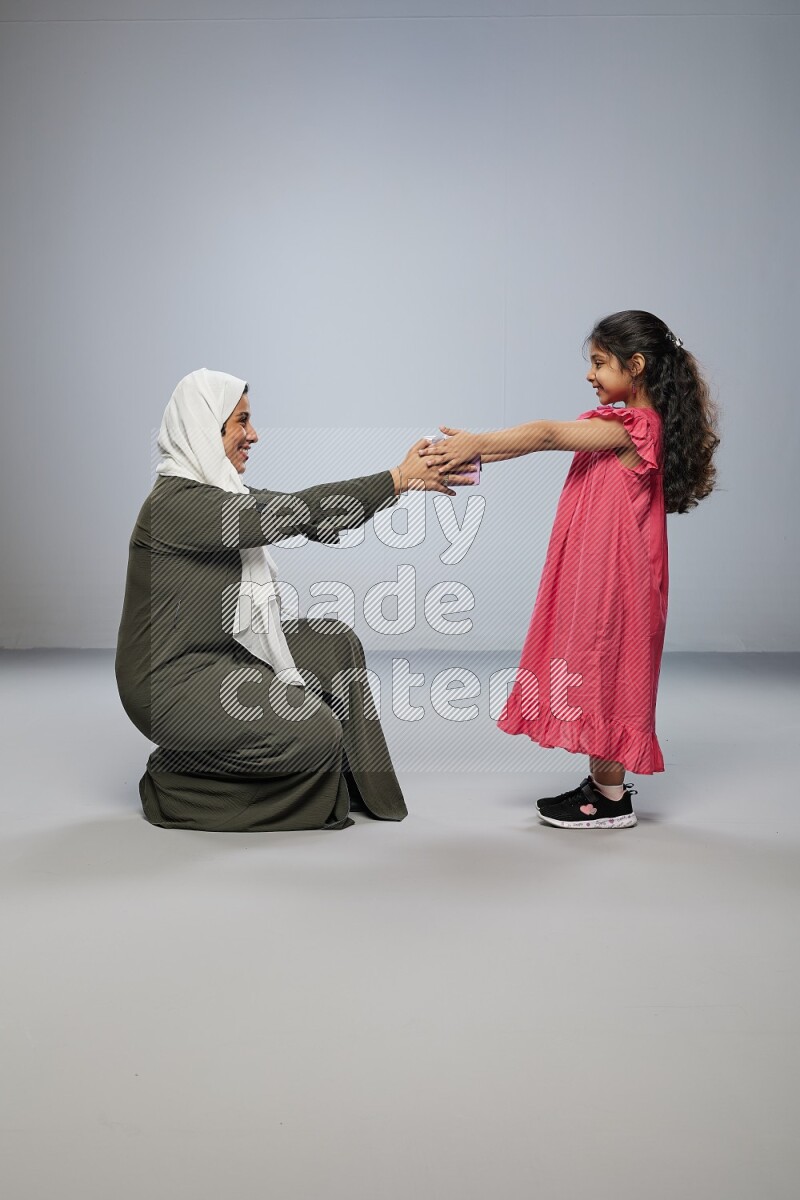 A girl giving a gift to her mother on gray background