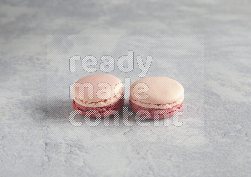 45º Shot of two Pink Litchi Raspberry macarons  on white  marble background