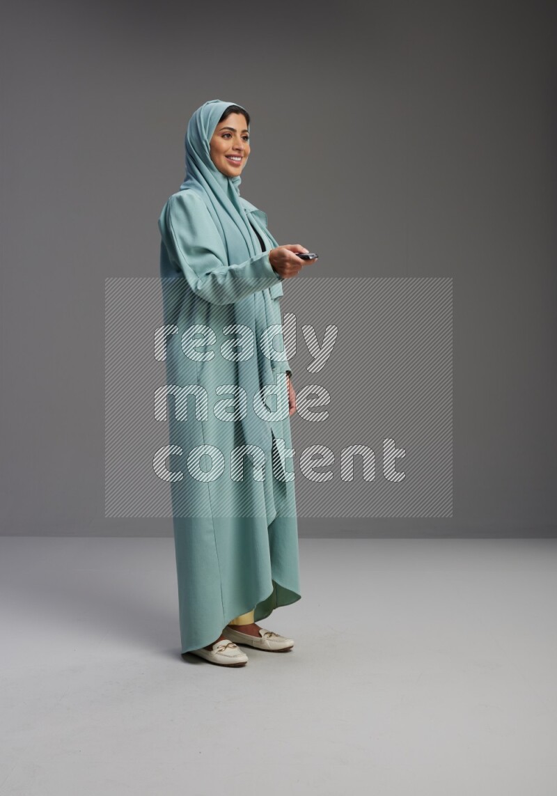 Saudi Woman wearing Abaya standing holding car key on Gray background