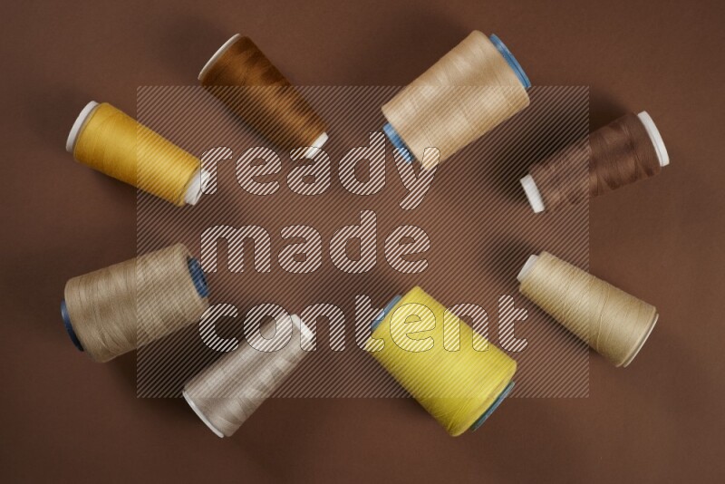 A yellow collection of sewing and tailoring tools arranged on a brown background