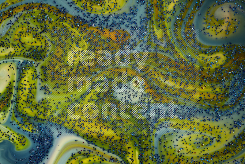 A close-up of sparkling blue glitter scattered on swirling blue and yellow background