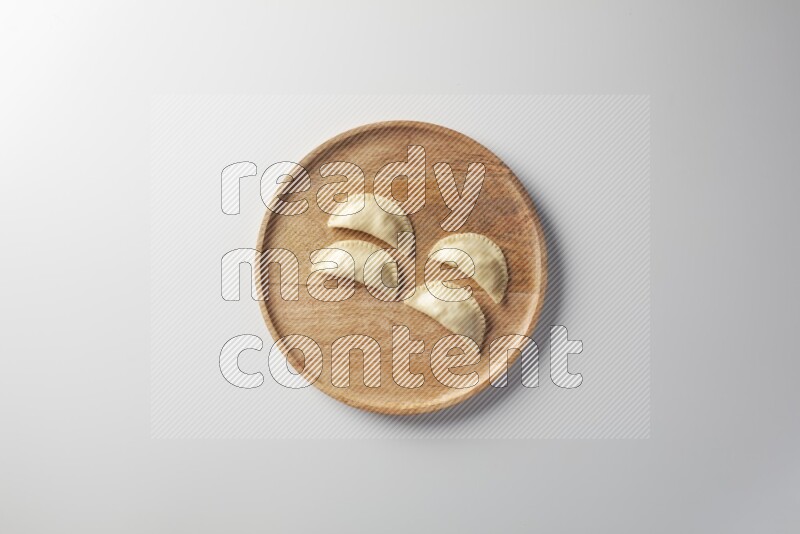 Four Sambosas on a wooden round plate on a white background
