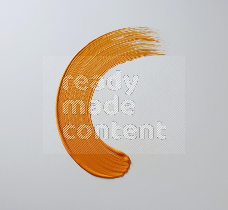 An orange half circular painting brush stroke on white background