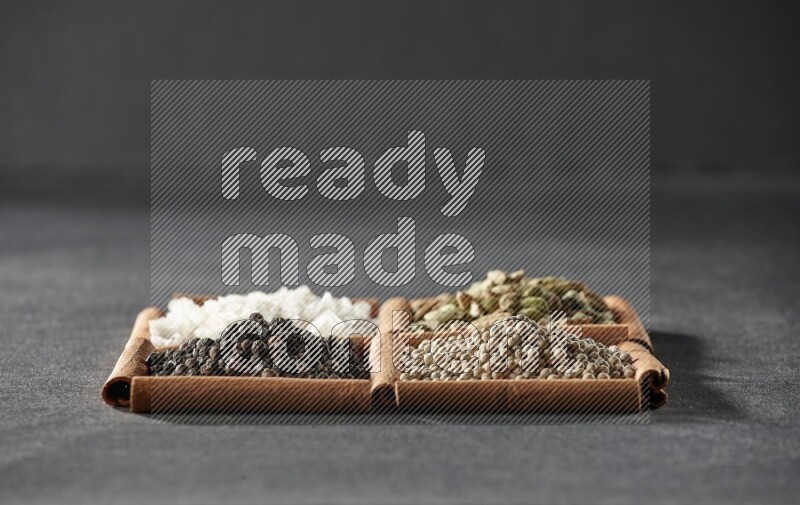 4 squares of cinnamon sticks full of black pepper, white pepper, cardamom and white salt on black flooring