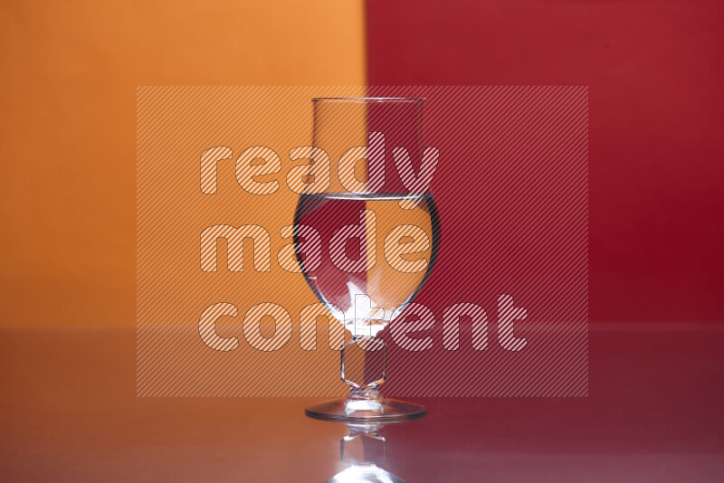 The image features a clear glassware filled with water, set against orange and red background