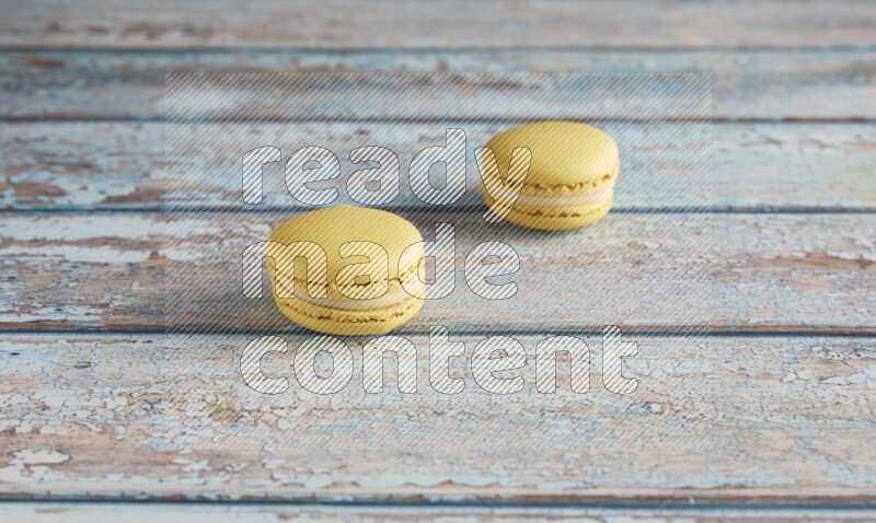45º Shot of two Yellow Lime macarons on light blue wooden background