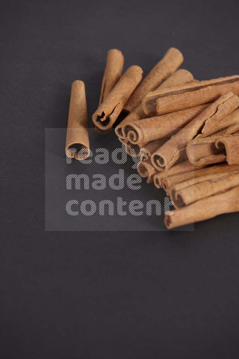 Cinnamon sticks stacked on black flooring