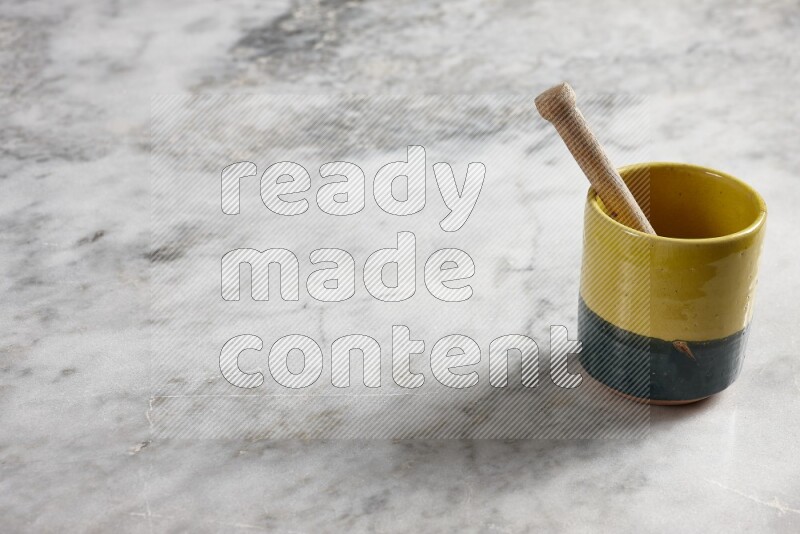 Multicolored pottery cup with wooden honey dipper in it on grey marble background