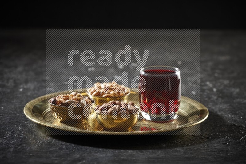 Nuts in metal bowls with Hibiscus on a tray in dark setup
