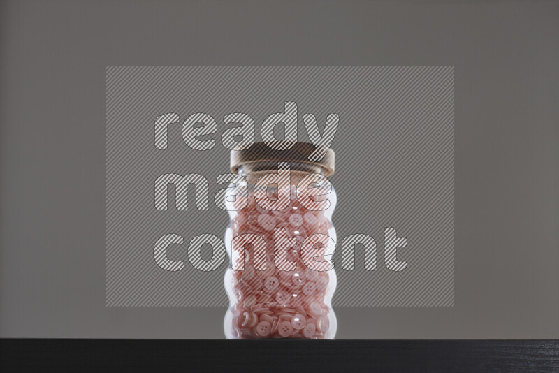 أزرار متنوعة في وعاء زجاجي علي خلفية سوداء