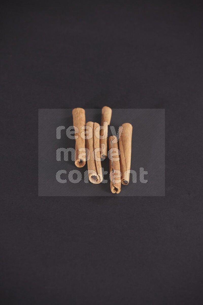 Cinnamon sticks stacked on black flooring