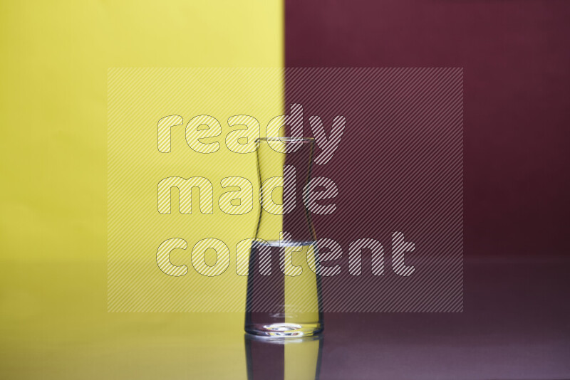 The image features a clear glassware filled with water, set against yellow and dark red background