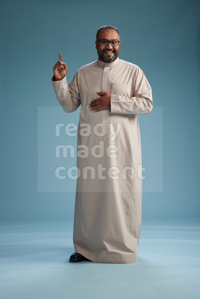 Saudi Man without shimag Standing Interacting with the camera on blue background