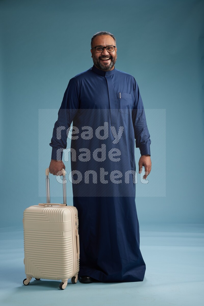 Saudi Man without shimag Standing pulling travel bag on blue background
