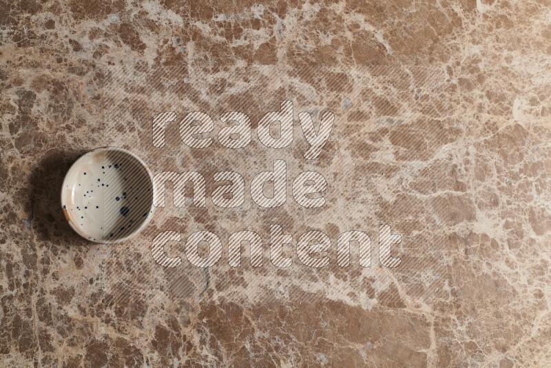 A multicolored pottery bowl on beige marble background