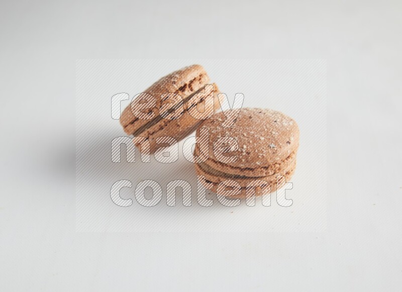 45º Shot of two Brown Hazelnuts macarons on white background