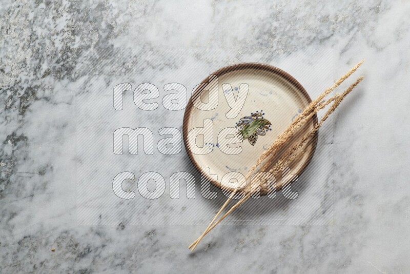 Wheat stalks on decorative pottery plate on grey marble background