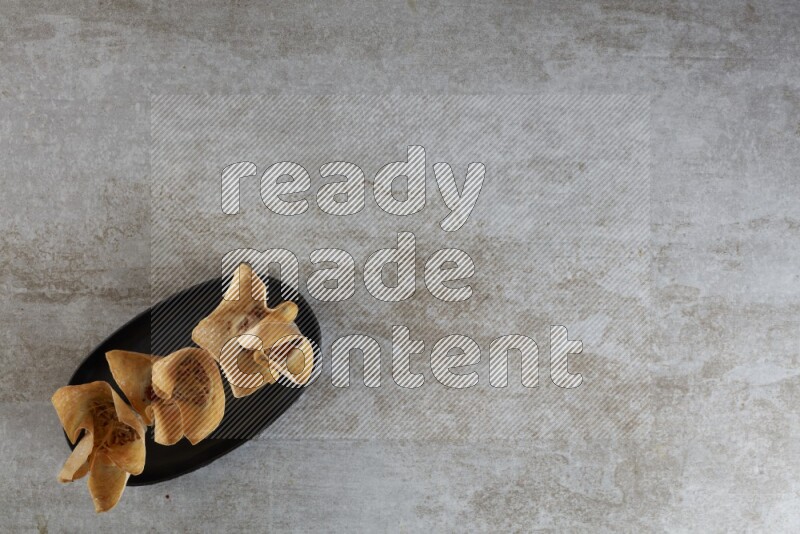 wonton cups on oval black ceramic plate on grey textured counter top