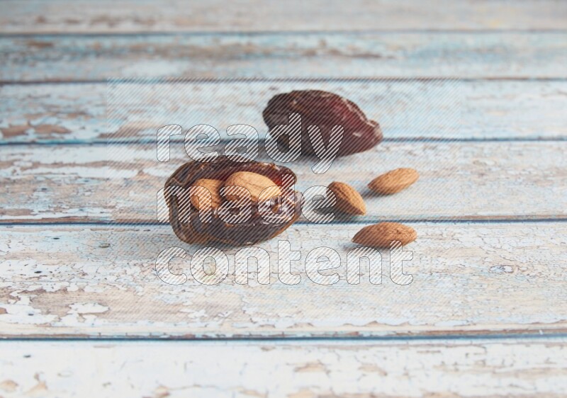 two almond stuffed madjoul dates on a light blue wooden background