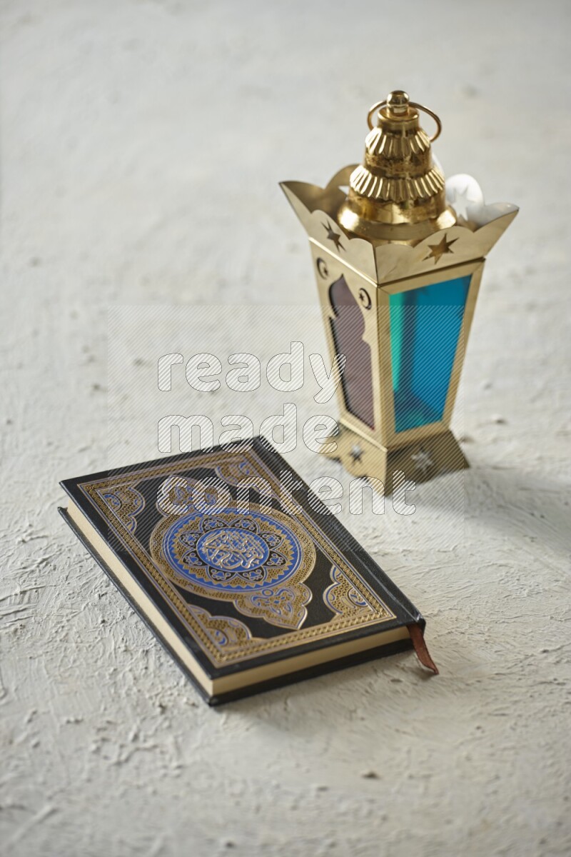 A golden lantern with different drinks, dates, nuts, prayer beads and quran on textured white background