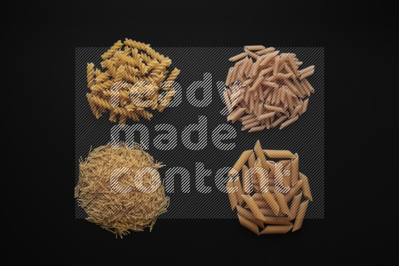 Different pasta types in bunches on black background
