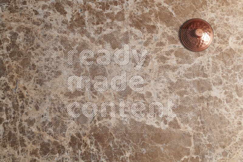 A small copper pot on beige marble background
