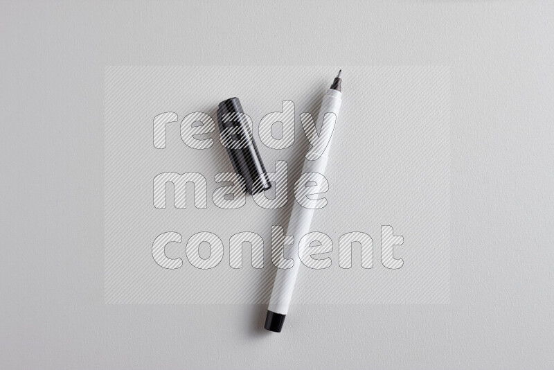 A close-up showing an open single coloring pen with a cap on grey background
