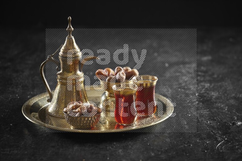 Nuts with dates and a drink on a metal tray in a dark setup