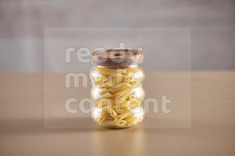 Raw pasta in glass jars on beige background