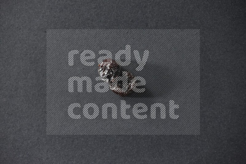 Two dried plums on a black background in different angles