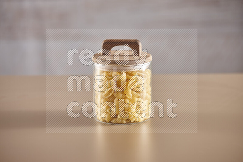 Raw pasta in glass jars on beige background