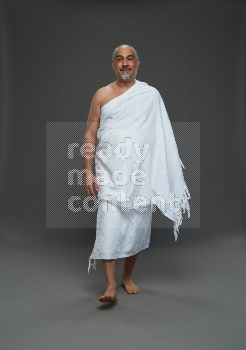 A man wearing Ehram Standing Interacting with the camera on gray background