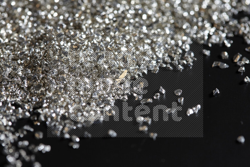 Silver shimmering fragments of glass scattered on a black background