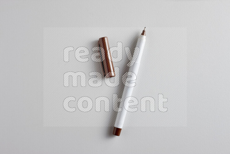 A close-up showing an open single coloring pen with a cap on grey background