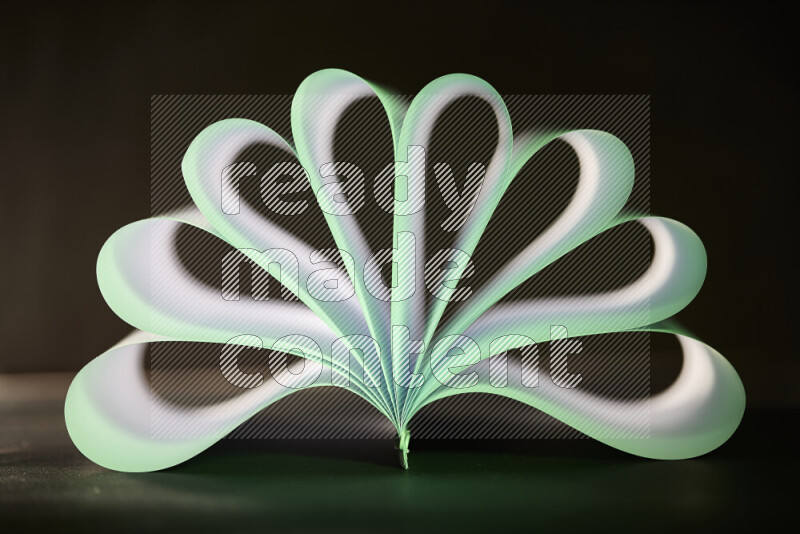 An abstract art piece displaying smooth curves in green and white gradients created by colored light