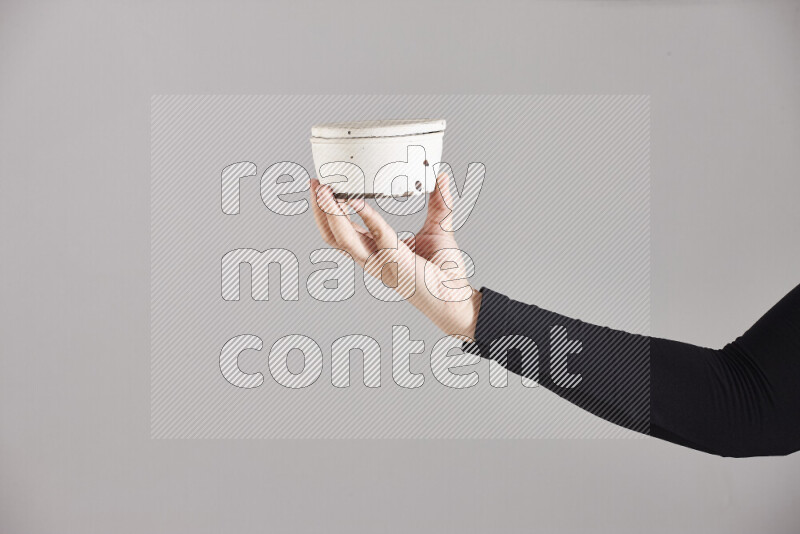 A woman in black abaya holding different pottery essentials in different positions