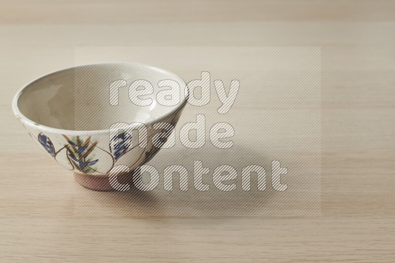 A decorative pottery bowl on light wooden background