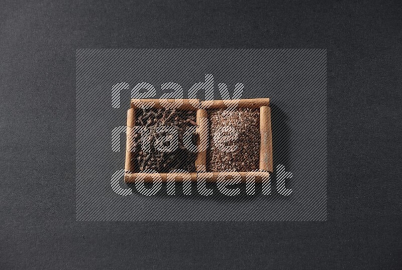 2 squares of cinnamon sticks full of flaxseeds and cloves on black flooring