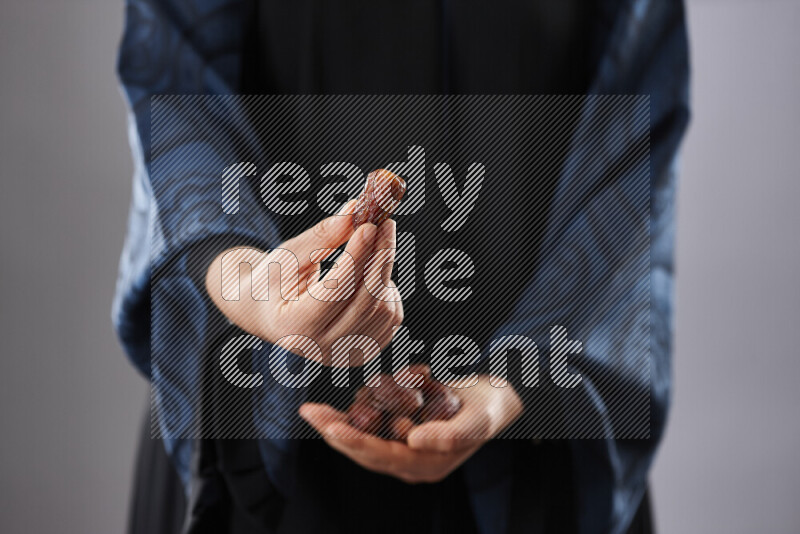 Woman in abaya holding dates in different positions